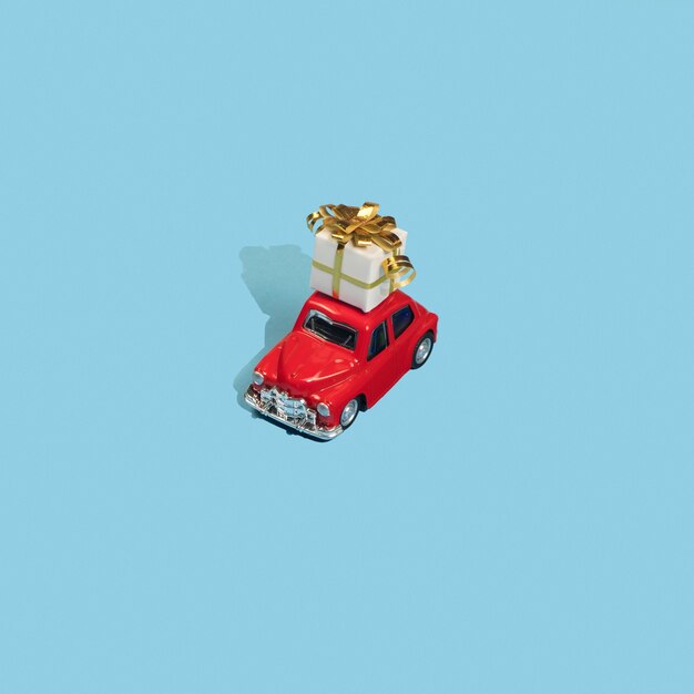 Gouden geschenk op dak rode speelgoedauto op blauwe achtergrond