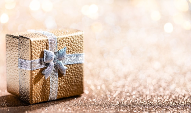 Gouden geschenkdoos met magisch licht op glitter bokeh achtergrond. Kerstvakantie.