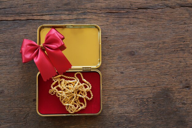 Gouden geschenkdozen met gouden ketting en lint op bruin houten achtergrond