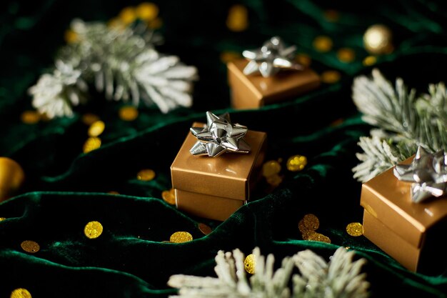 Gouden geschenkdozen met zilveren lint op glanzende velur groene achtergrond met kerstversiering Plat leggen Kopieer ruimte Trouwen met Kerstmis