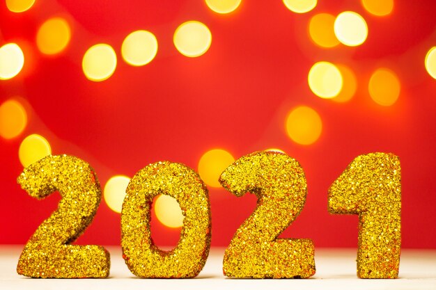 Gouden glinsterende nummers 2021 met bokeh op rode achtergrond. Vrolijk kerstfeest en een gelukkig nieuw jaar. Kopieer ruimte.