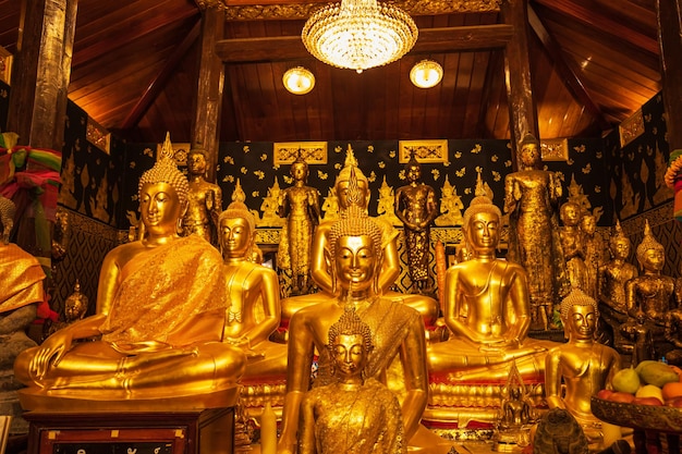 Gouden groep boeddha kijkt naar standbeeld meditatie zittend met een Gouden Boeddha achtergrond omhoog naar beneden en gaat zitten