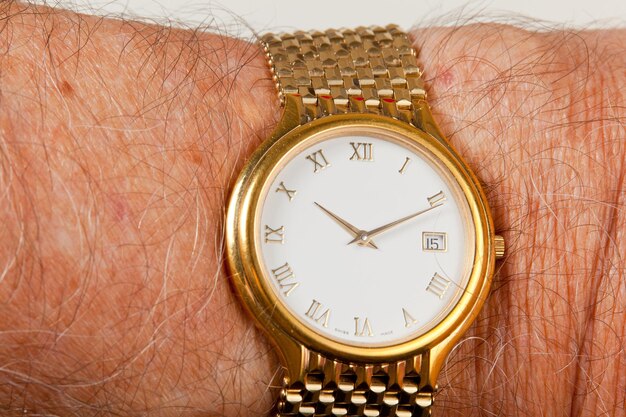 Gouden horloge met wit gezicht op harige pols