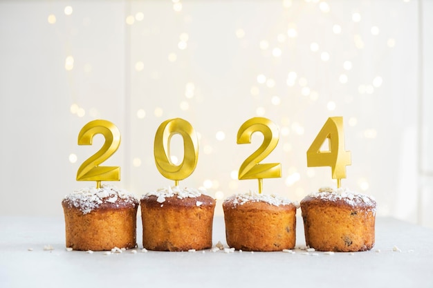 Foto gouden kaarsen met het nummer 2024 bovenop de cupcakes vrolijk kerstfeest en gelukkig nieuwjaar