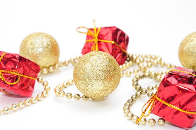 Gouden kerstballen en geschenken in rode verpakking gebonden door een ketting op een afgelegen witte achtergrond