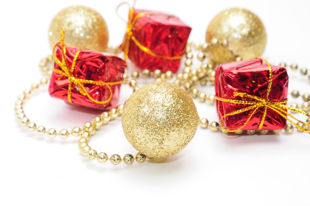 Gouden kerstballen en geschenken in rode verpakking gebonden door een ketting op een afgelegen witte achtergrond