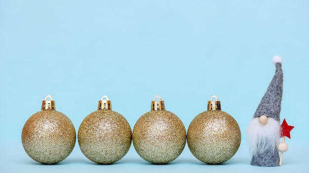 Foto gouden kerstballen met een kleine kabouter op een blauwe achtergrond, kopieer ruimte