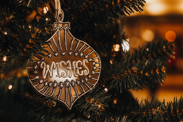 Gouden kerstspeelgoed met tekstwensen die aan de boom hangen Gouden bokehlichten op feestelijke achtergrond