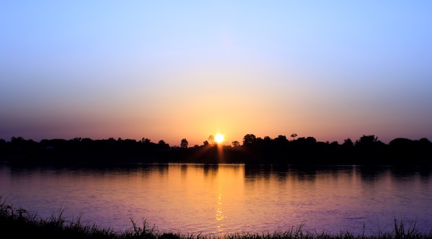 Gouden licht op zon die met licht op de rivier wordt geplaatst.