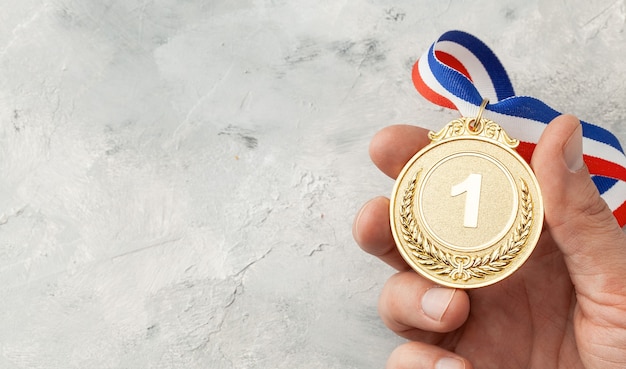 Foto gouden medaille. de prijs voor de eerste plaats met een lint dat een man in zijn hand houdt.