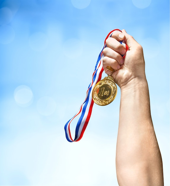 Foto gouden medaille met lint in de hand op achtergrond