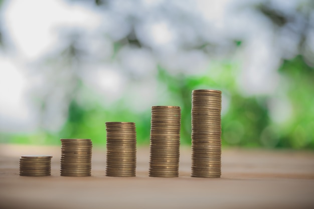 Gouden munten en plant met groene bokeh licht in het besparen van geld concept