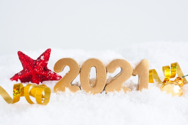 Gouden nummers 2021, rode stralende ster en gouden serpentijn in de sneeuw.