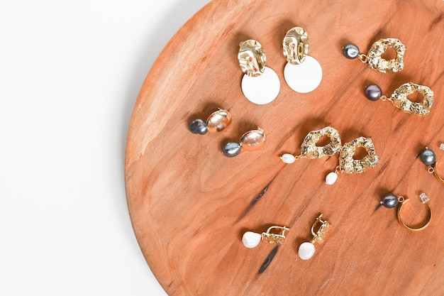 Gouden oorbellen Dames39s sieraden Mooie gouden tinten oorbellen met parels op een houten dienblad Platliggend bovenaanzicht