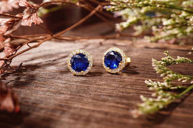 Gouden oorbellen geïsoleerd, met blauwe kristallen en diamanten. Mooie oorbellen op houten ondergrond