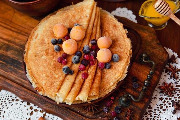 Gouden pannenkoeken met bevroren fruit, decor en honing in rustieke stijl