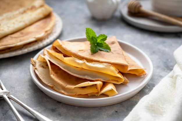 Gouden pannenkoeken met jam en honing, op grijze achtergrond.