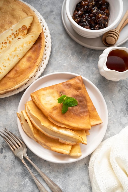 Gouden pannenkoeken met jam en honing, op grijze achtergrond.