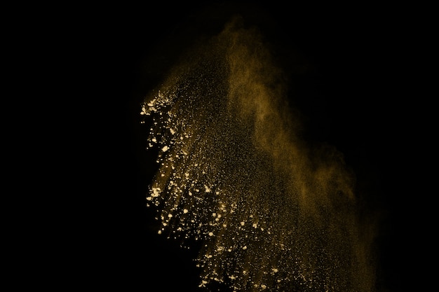 Gouden poederexplosie op zwarte achtergrond. Beweging bevriezen.