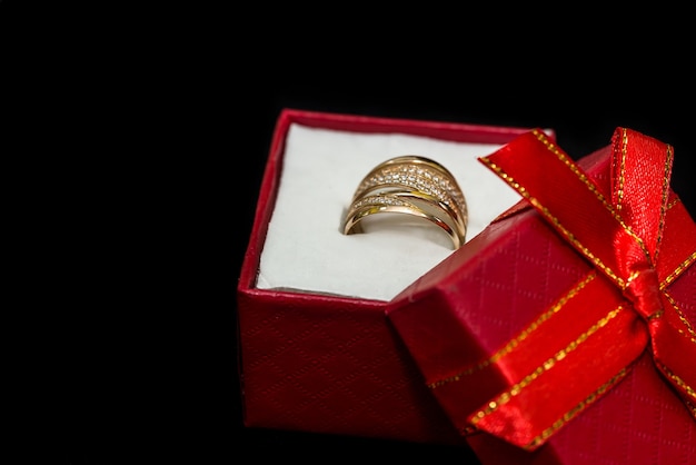 Gouden ring in kleine rode doos is geïsoleerd op zwart oppervlak