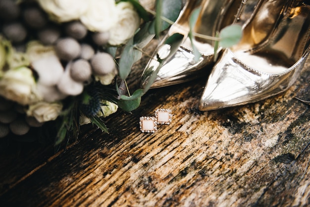 Foto gouden schoenen en huwelijksboeket van de bruid op natte houten