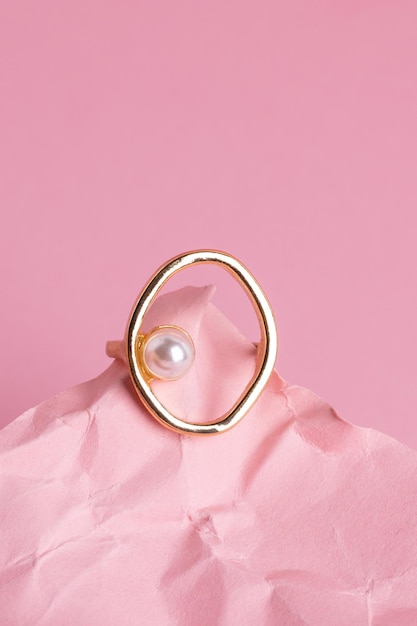 Gouden sieraden op een roze achtergrond Stijlvolle gouden ring met parel op roze achtergrond Product foto