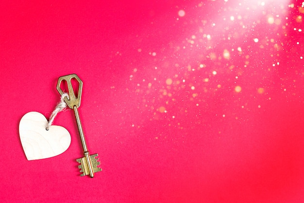 Gouden sleutel met houten tag in de vorm van een hart op een rode achtergrond