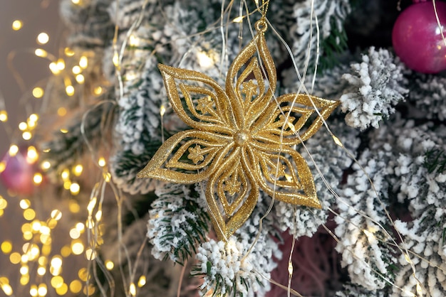 Gouden sneeuwvlok op een tak van een kunstmatige kerstboom close-up. Details van de kerstboom.