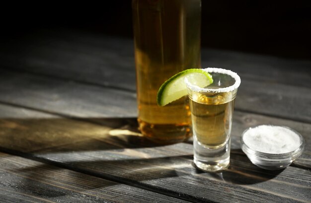 Foto gouden tequila geschoten met limoen en zout op houten tafel