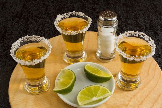 Gouden tequila-schoten op het ronde houten bord