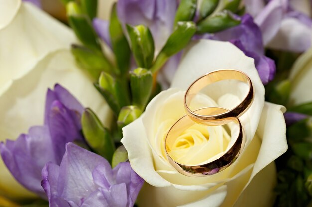 Gouden trouwringen aan een boeket bloemen voor de bruid