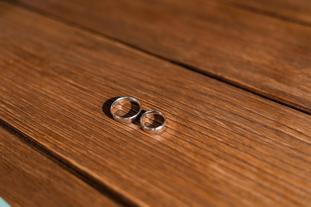 Gouden trouwringen liggen op een houten tafel