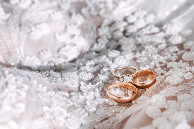 Gouden trouwringen met diamanten liggen op de jurk van de bruid