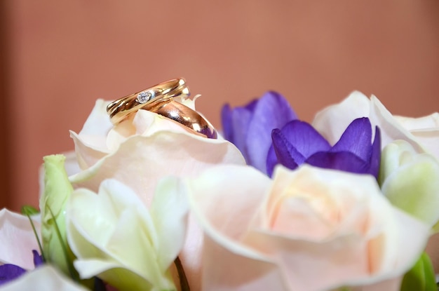 Gouden trouwringen op een witte bloem van een mooi bruidsboeket met witte en blauwe bloemen close-up