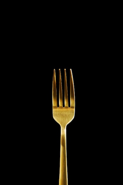 Foto gouden vork geïsoleerd op zwarte achtergrond close-up van een vork met kopie ruimte