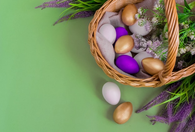 Foto gouden, witte, paarse eieren in een mandje