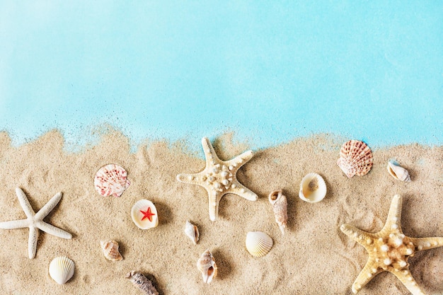 Gouden zeezand met zeesterren en schelpen op pastelblauw bovenaanzicht als achtergrond