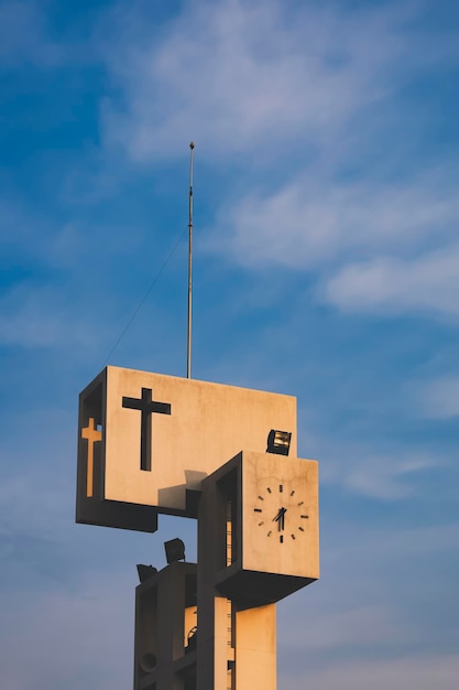 Gouden zonlicht op het oppervlak van de oude katholieke betonnen klokkentoren tegen blauwe hemelachtergrond