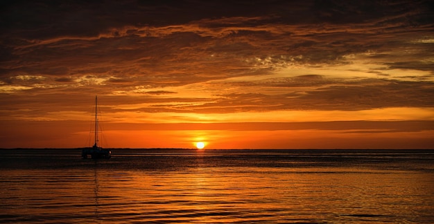 Gouden zonsondergang bij het overzeese landschap met zonsondergang over de oceaanbootzeilboot