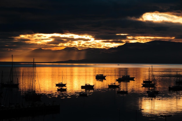 Foto gouden zonsondergang boven de zee met silhouet van boten in de buurt van de baai