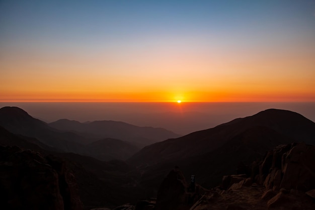 gouden zonsondergang tussen wolken en bergen De ondergaande zon aan de horizon