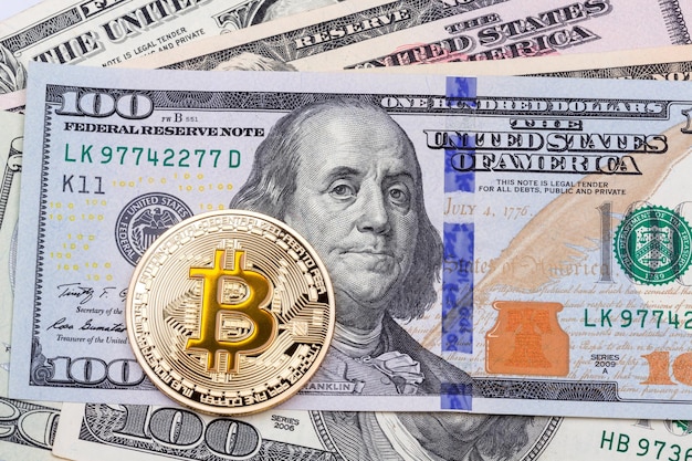 Goudgele bitcoin op honderd bankbiljetten achtergrond. Hoge resolutie foto.