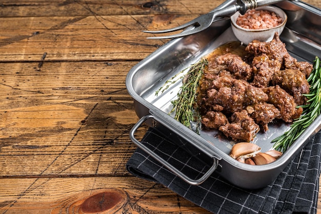 Goulash from lamb and beef meat in a tray with herbs. Wooden background. Top view. Copy space.