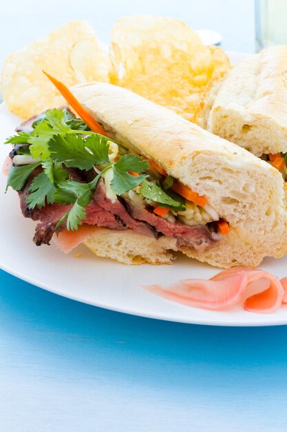 Gourmet banh-mi sandwich with chips on the side.