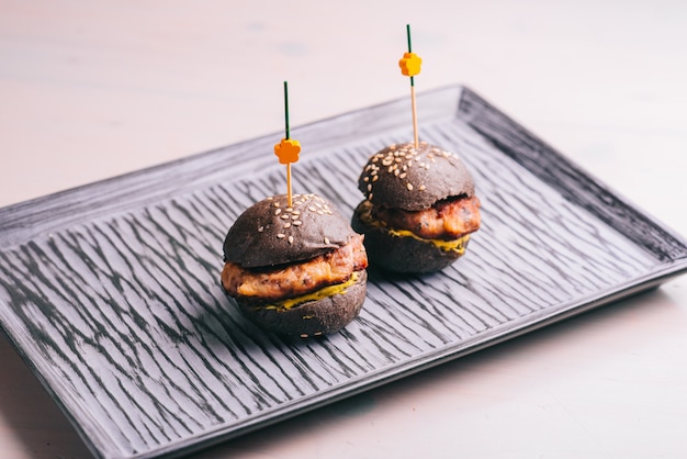 Gourmet beef mini hamburger with black bread on a plate