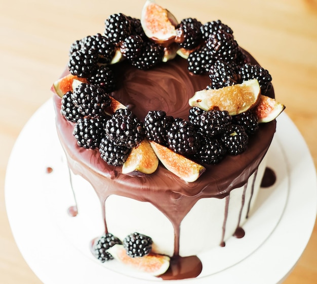 A gourmet cake drenched in chocolate and garnished with\
blackberries and figs holiday sweets