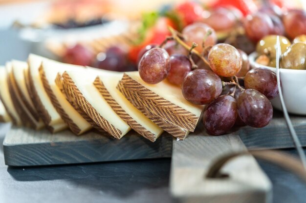 Gourmet cheese, crackers, and fruit on a wood cutting board served as an appetizer.