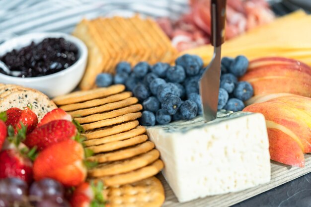 Gourmet cheese, crackers, and fruit on a wood cutting board served as an appetizer.