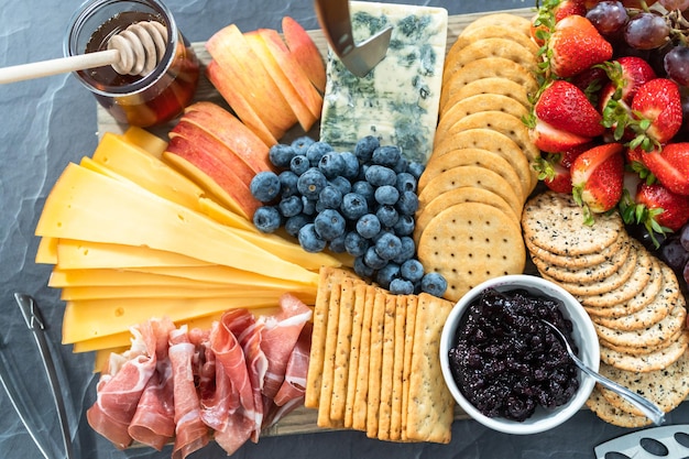 Gourmet cheese, crackers, and fruit on a wood cutting board served as an appetizer.