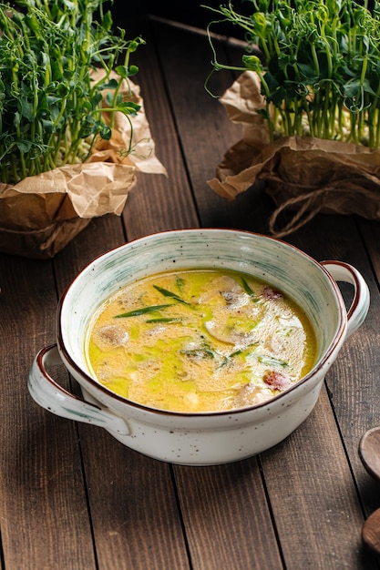 Gourmet chicken cream soup with herbs on wooden background